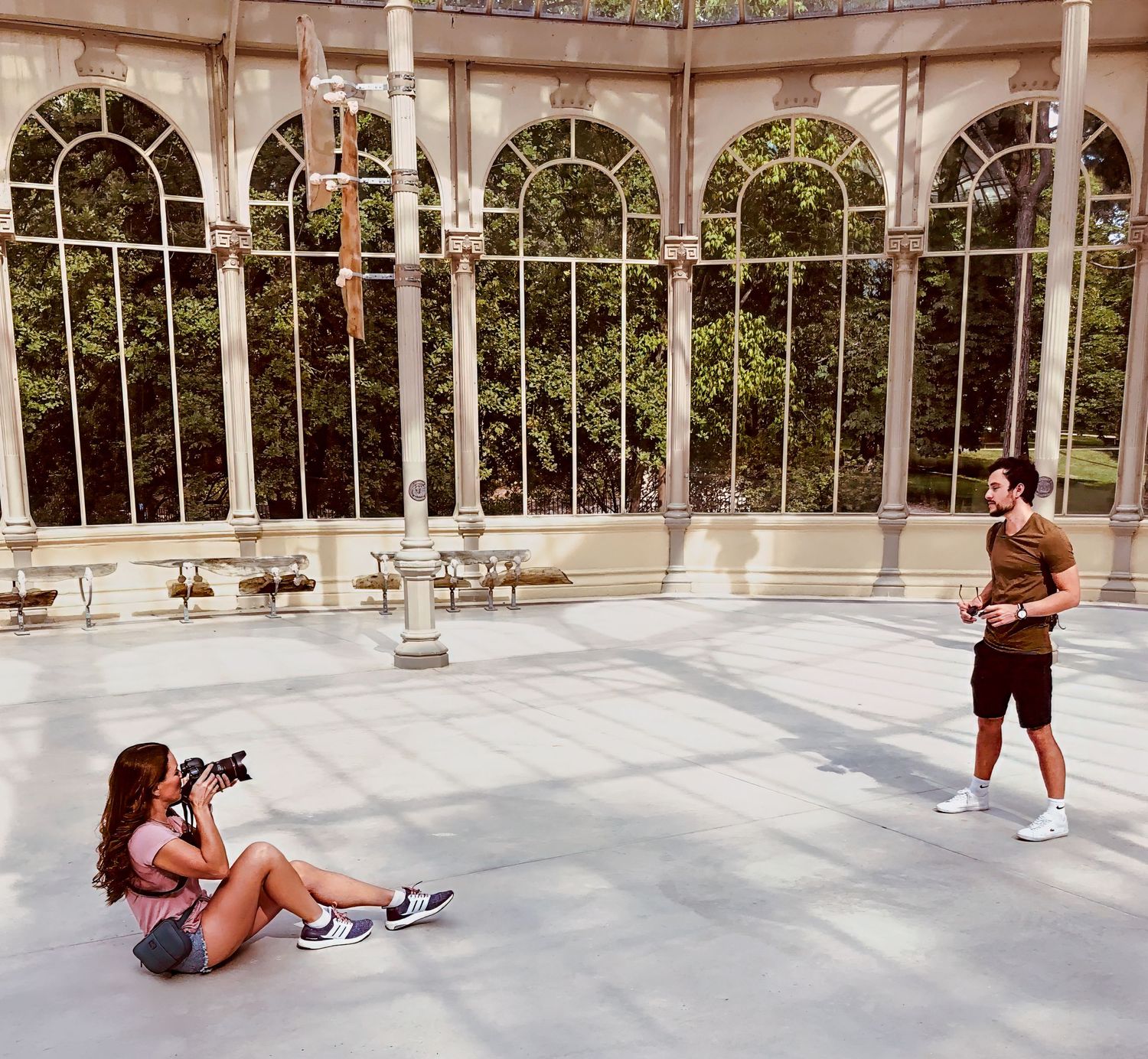 Photographers working in an ornate colonnade with arched windows and natural lighting.