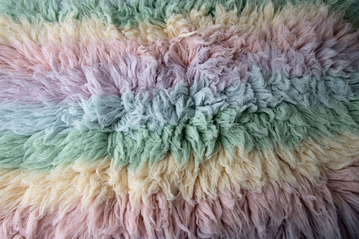 Soft rainbow pastel fluffy faux fur fabric texture in pink, purple, green, and yellow colors.