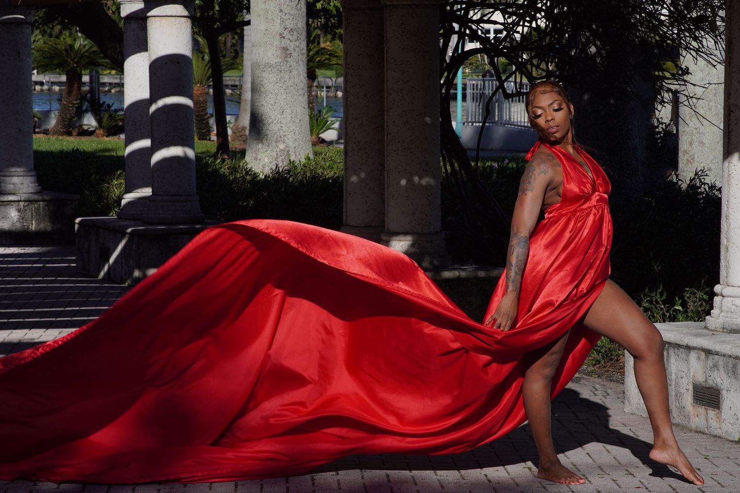 Dramatic flowing red dress creates movement against urban architectural backdrop.