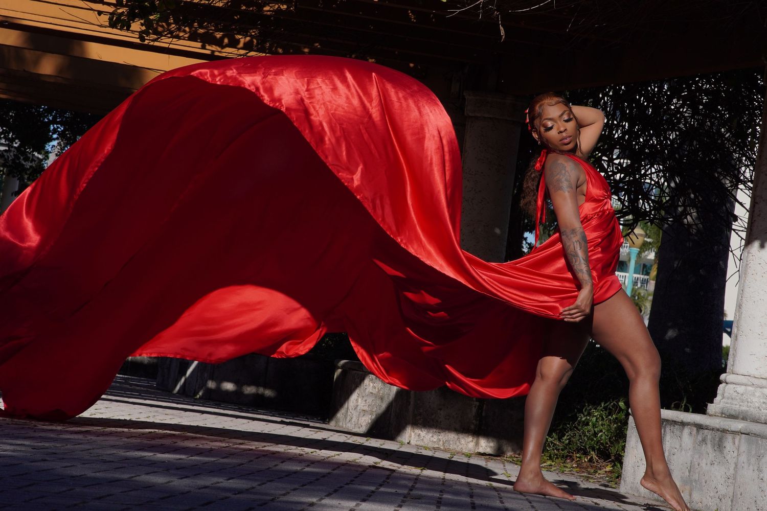 Bold red flowing fabric creates dynamic movement in outdoor fashion shoot.