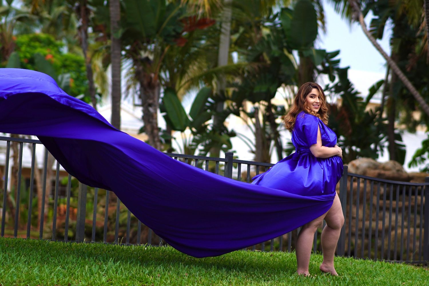 Flowing purple dress creates dramatic movement in tropical garden setting.