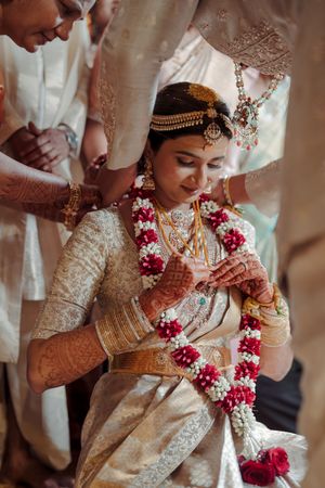 Traditional Indian bride wearing ornate jewelry and floral garlands during wedding ceremony rituals.