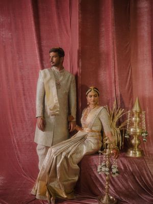 Traditional wedding decor setup with gold candelabras and cream colored drapes against a burgundy backdrop.