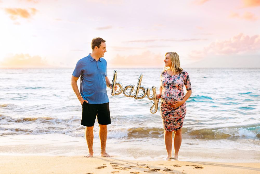 wailea maternity photographer. Family enjoying sunset beach photoshoot in coordinated outfits with waves in background.