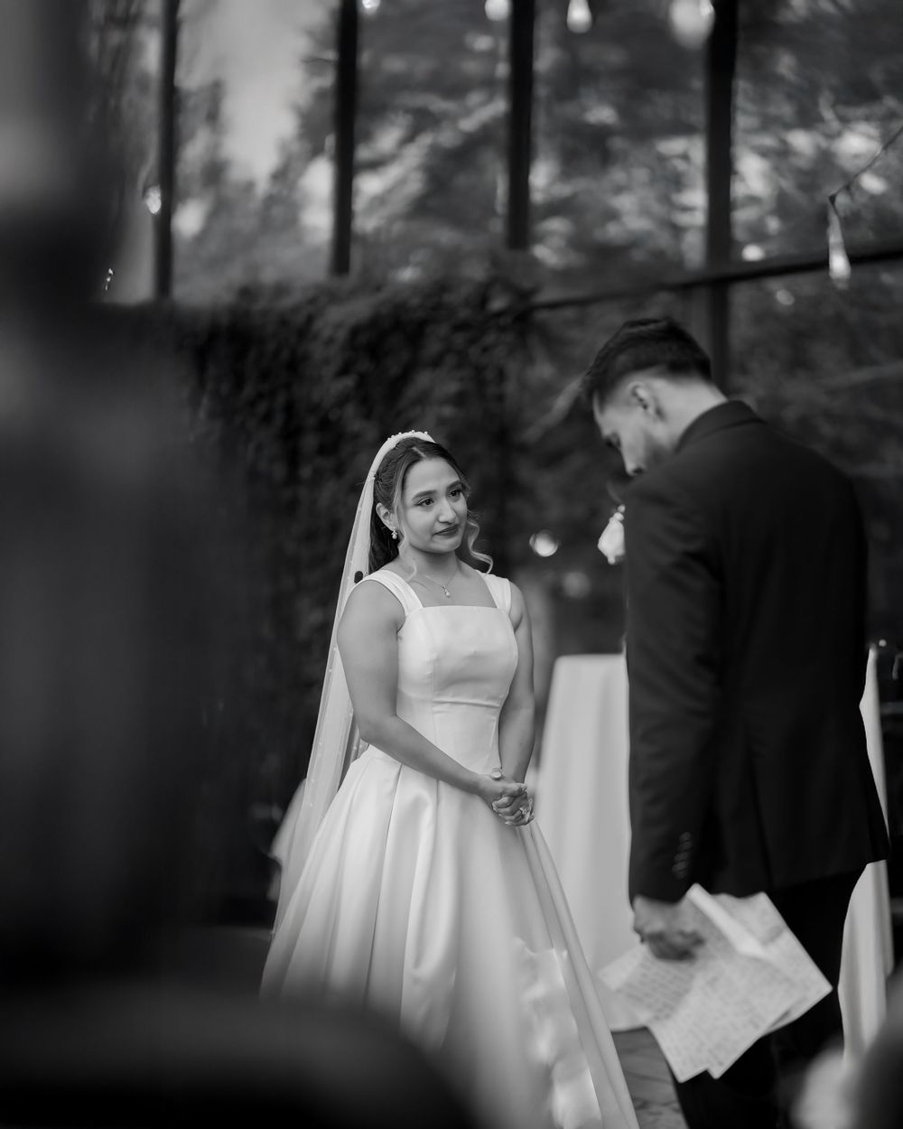 Black and white wedding ceremony photo with elegant decor and soft lighting.