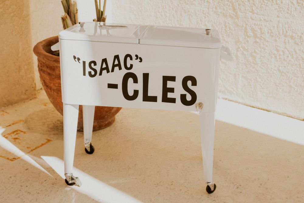 White vintage-style cart with 'ISAAC-CLES' text displayed against a light wall.