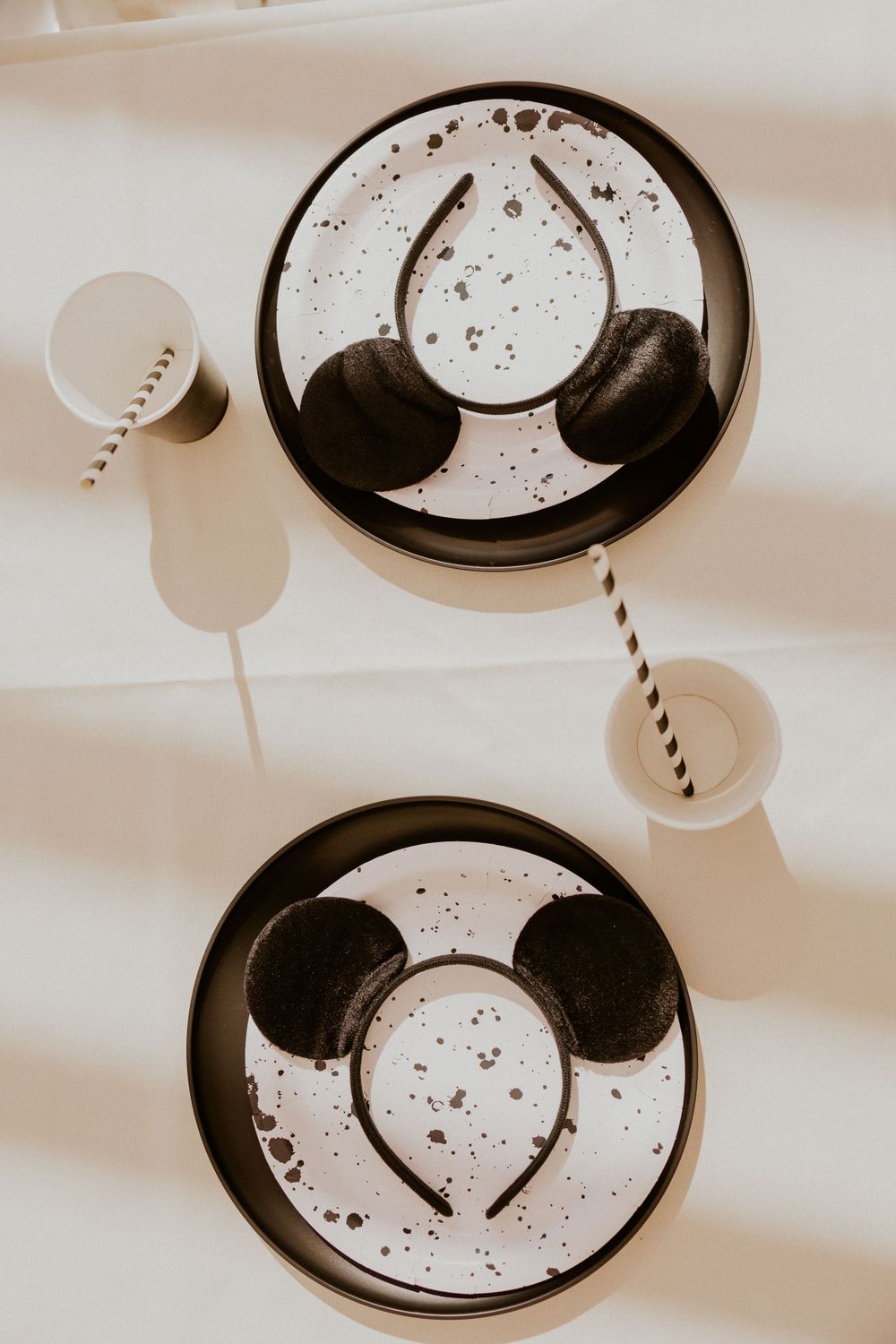 Overhead view of Mickey Mouse themed plates with black and white striped straws.
