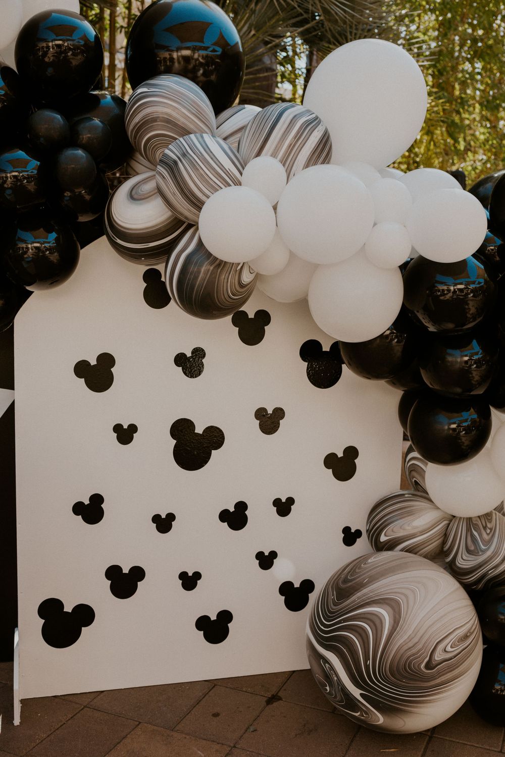 Mickey Mouse themed balloon arch installation with black, white and marble patterned balloons.