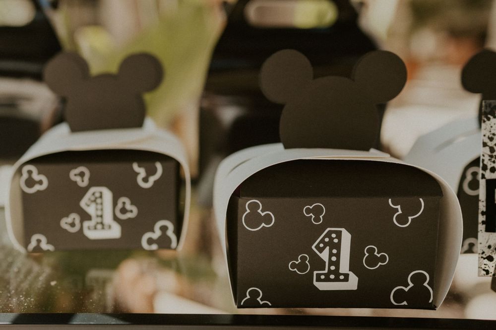 Close-up view of black Mickey Mouse themed party favor boxes decorated with hearts and the number one.
