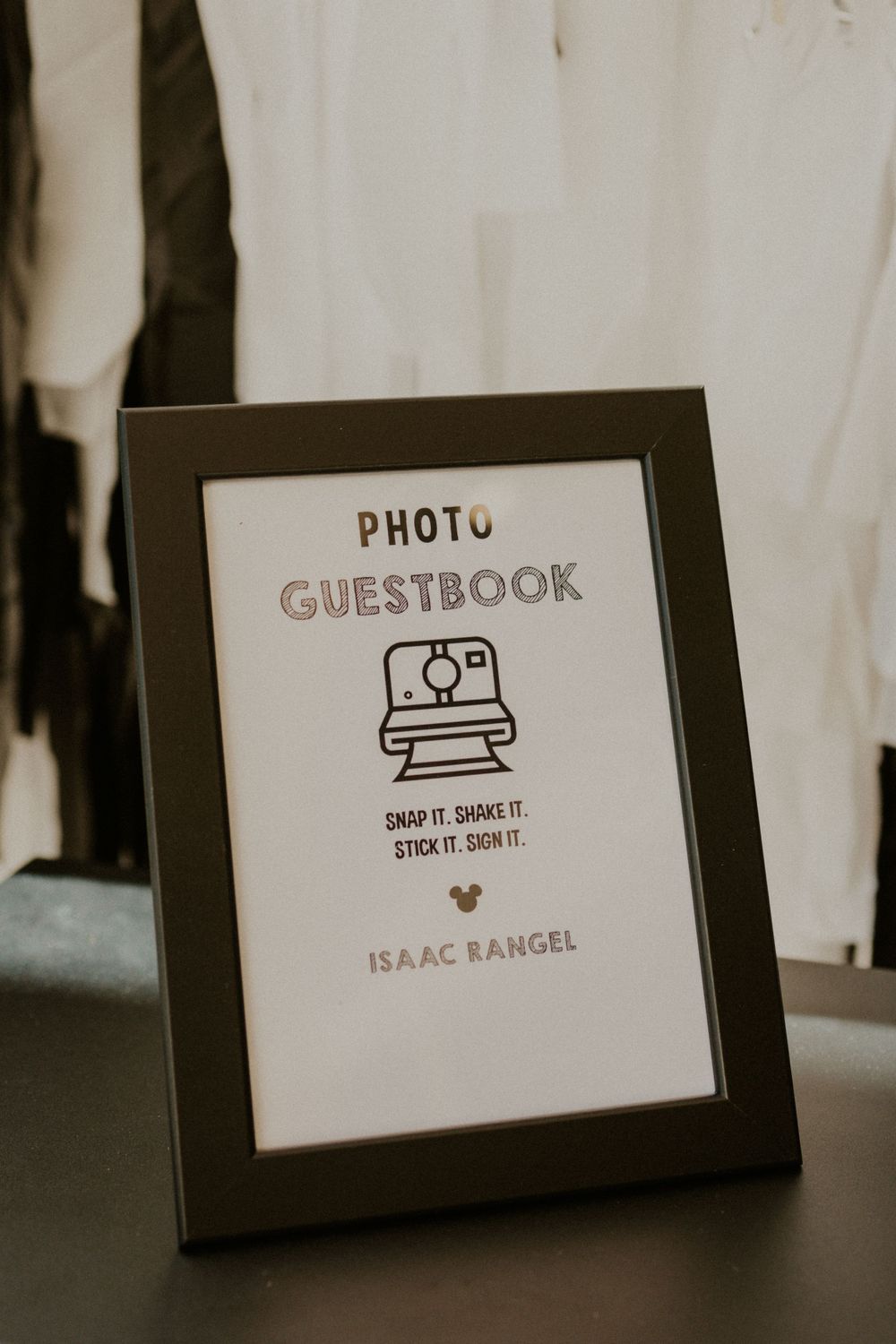 A framed photo guestbook sign with camera icon and instructions for guests.