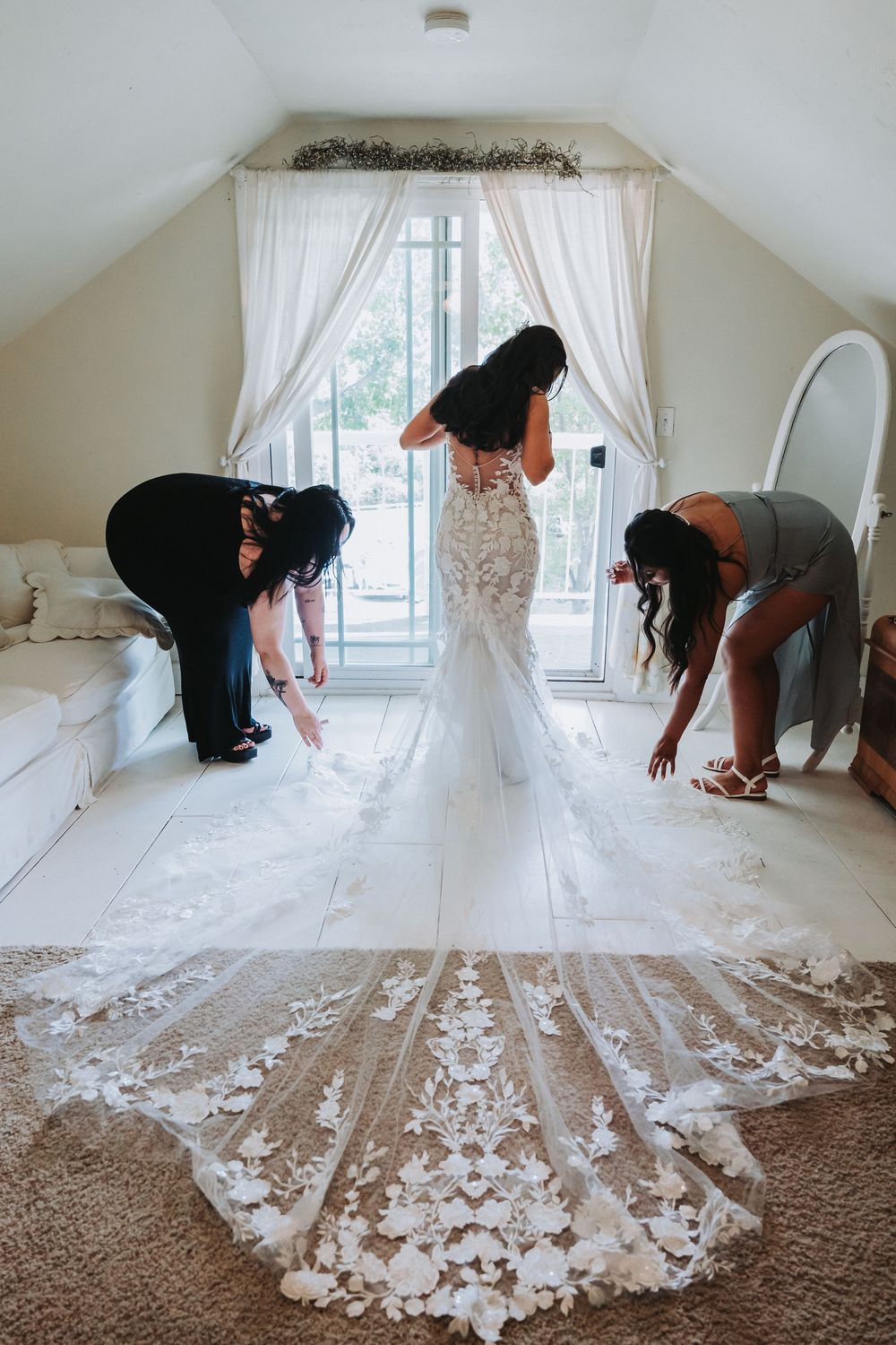 Bridesmaids helping bride with dress