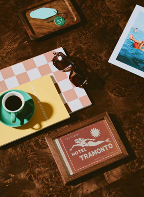 Vintage hotel sign and coffee cups arranged on a dark wooden surface with scattered photographs and papers.