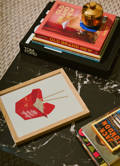 Minimalist red art prints displayed on black marble surface with vintage books and brass decor elements.