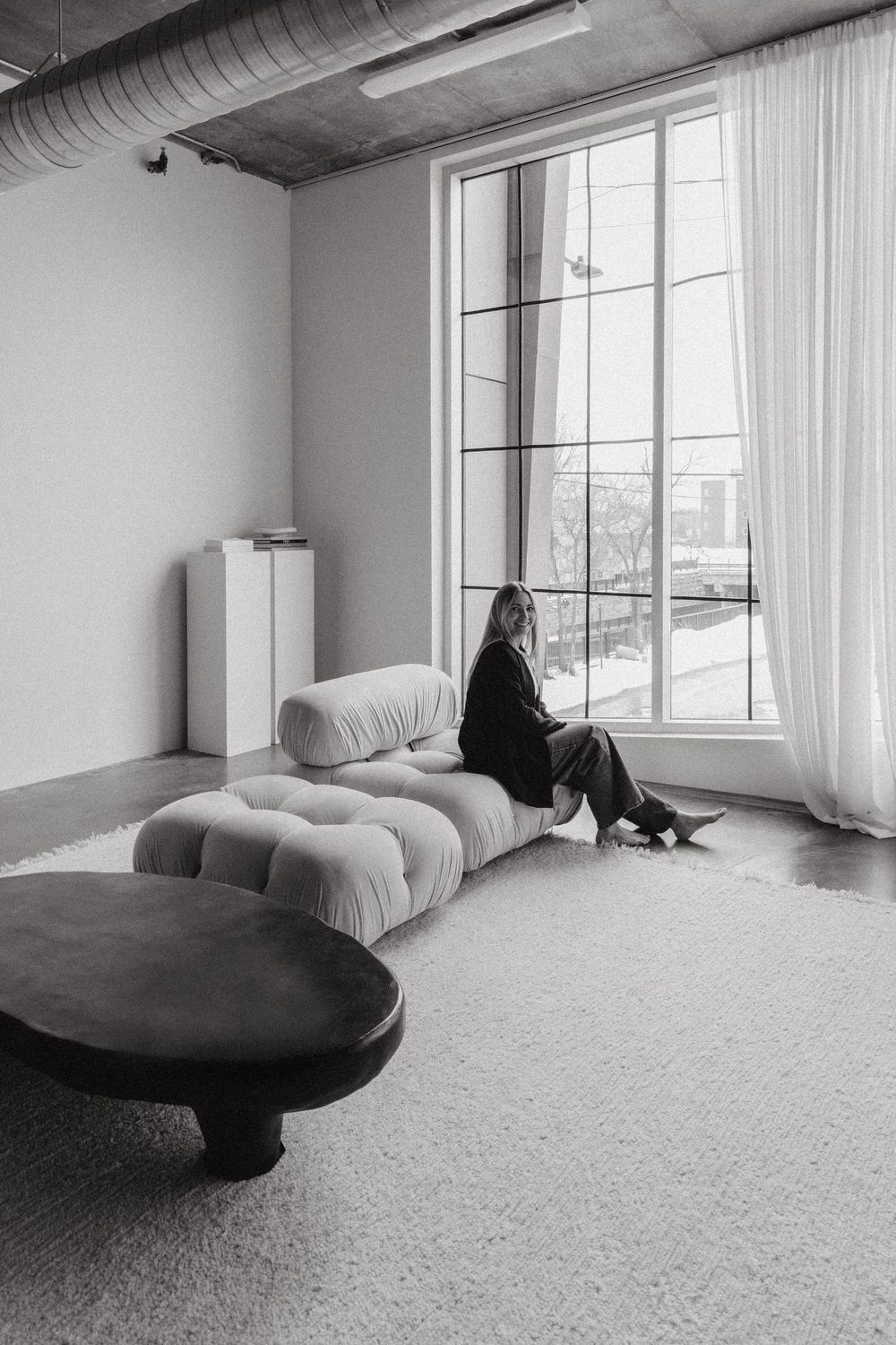 Black and white panoramic series of a minimalist living room with white walls, carpeting and a curved contemporary sofa.