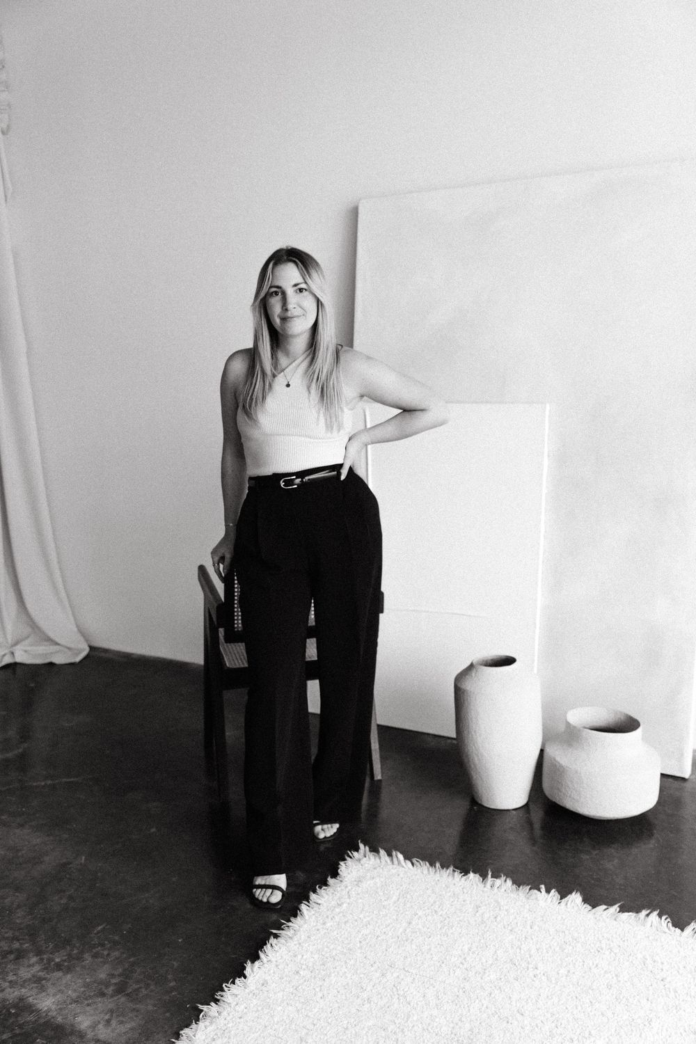 Four black and white photographs arranged in sequence show a figure in dark clothing against a minimalist white backdrop.