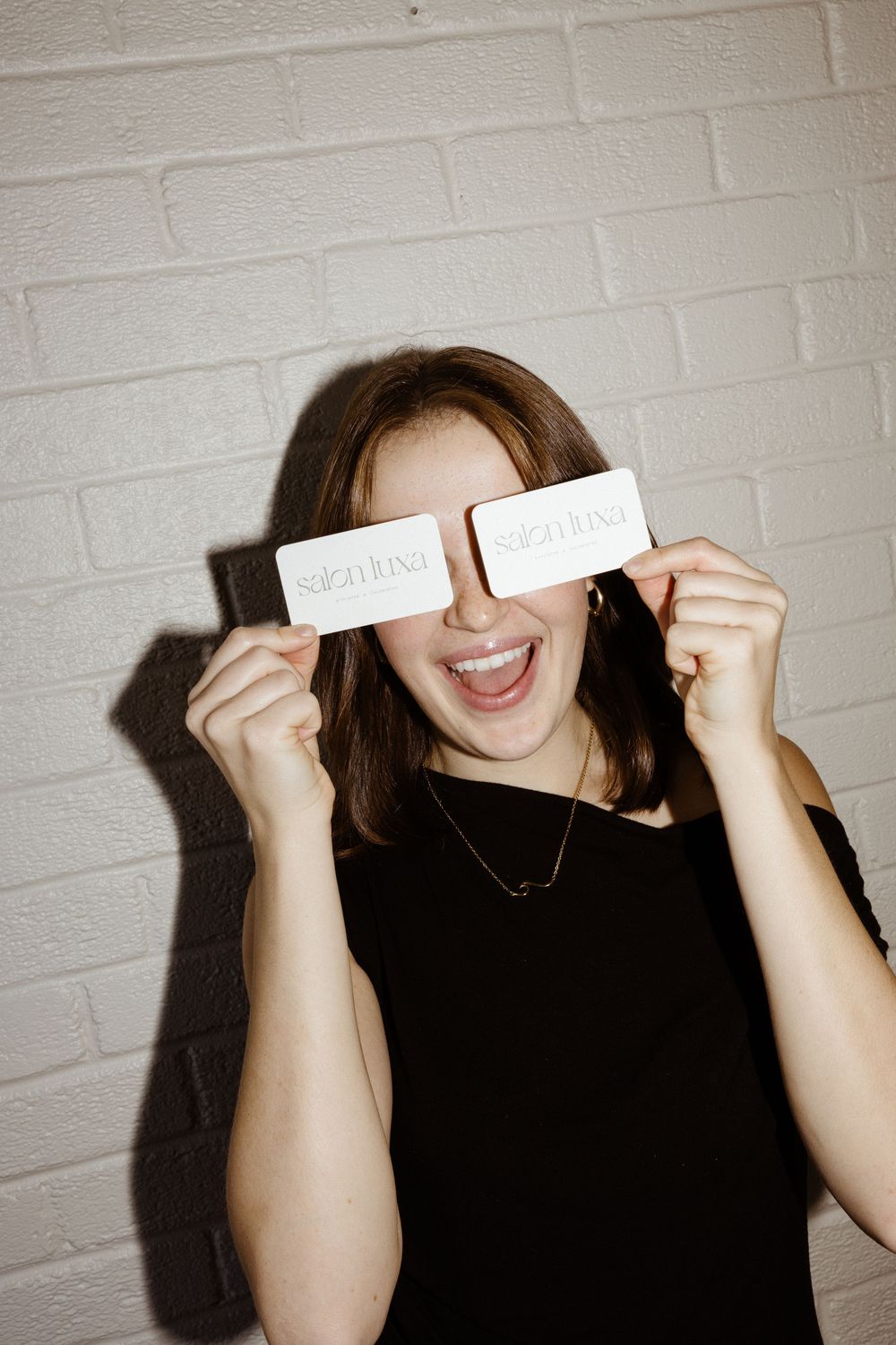 A sequence of photos showing someone holding white paper strips over their eyes against a white brick wall background.