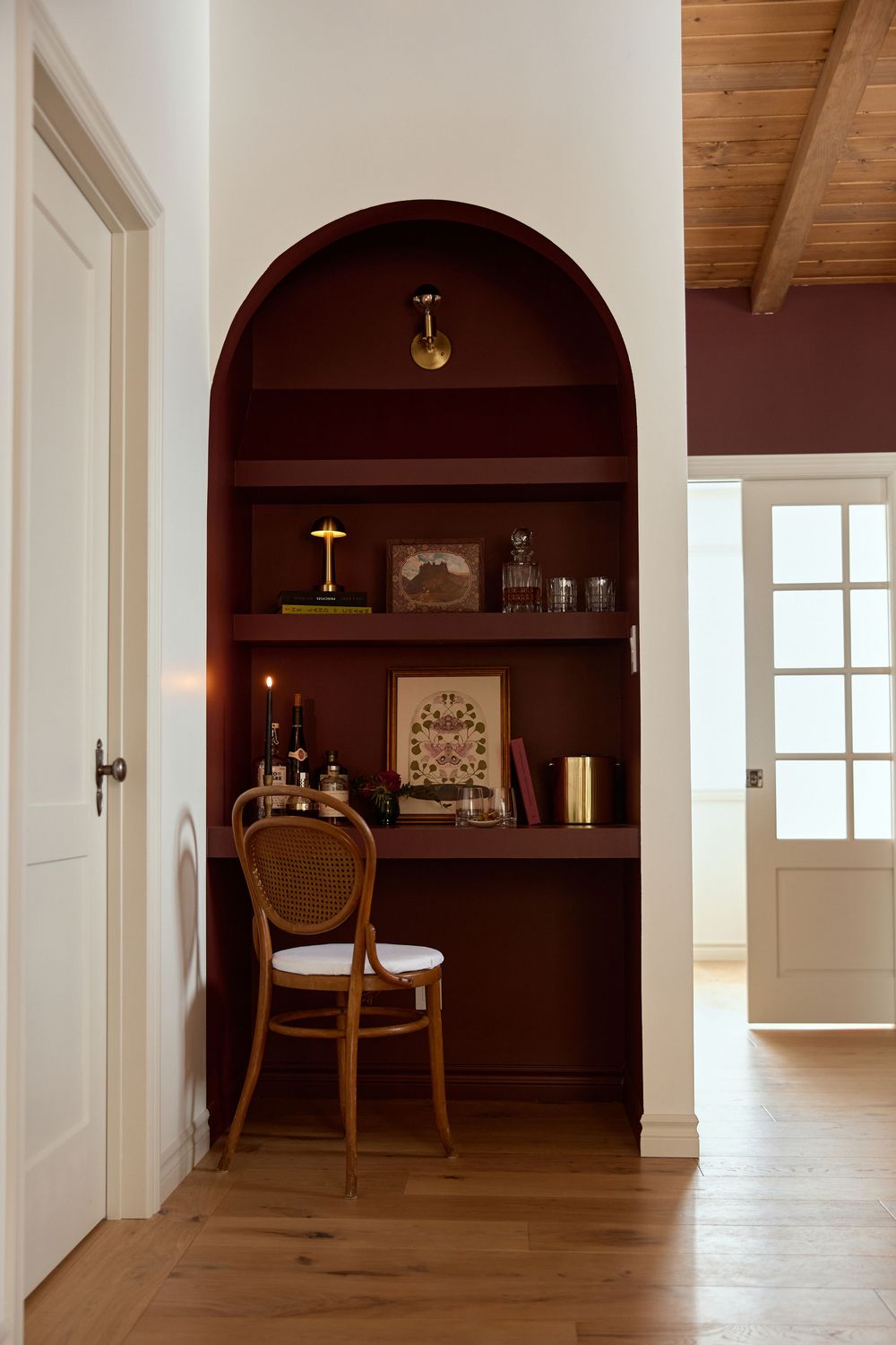 A cozy built-in alcove with wooden shelving, vintage chair, and decorative items creates an intimate reading nook.
