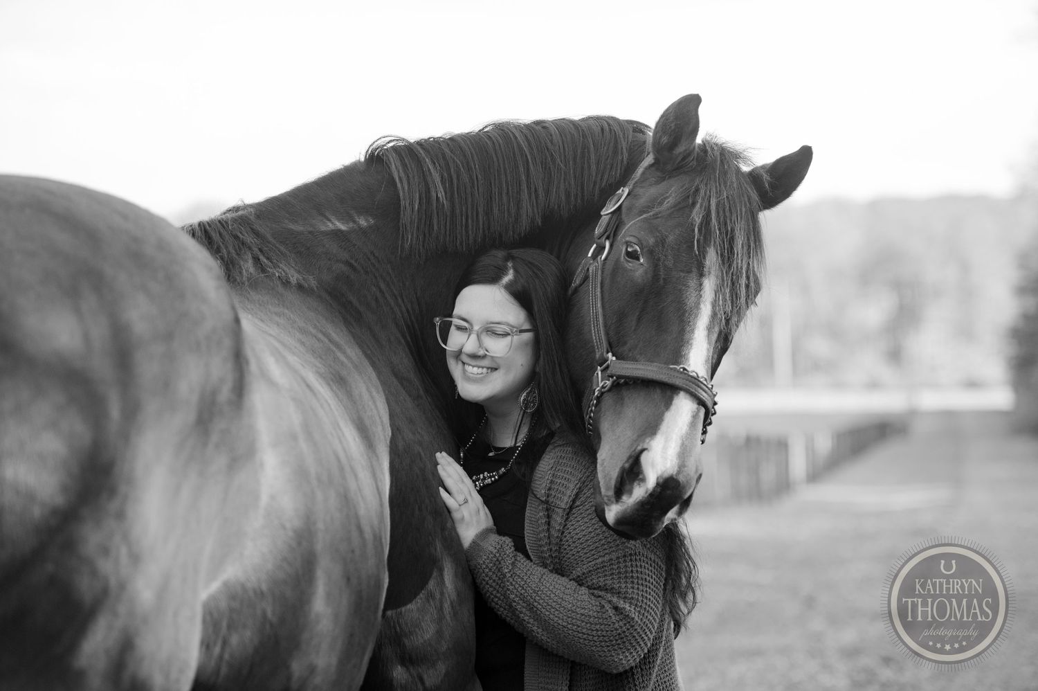 A black and white portrait capturing an intimate moment between a horse and their companion.