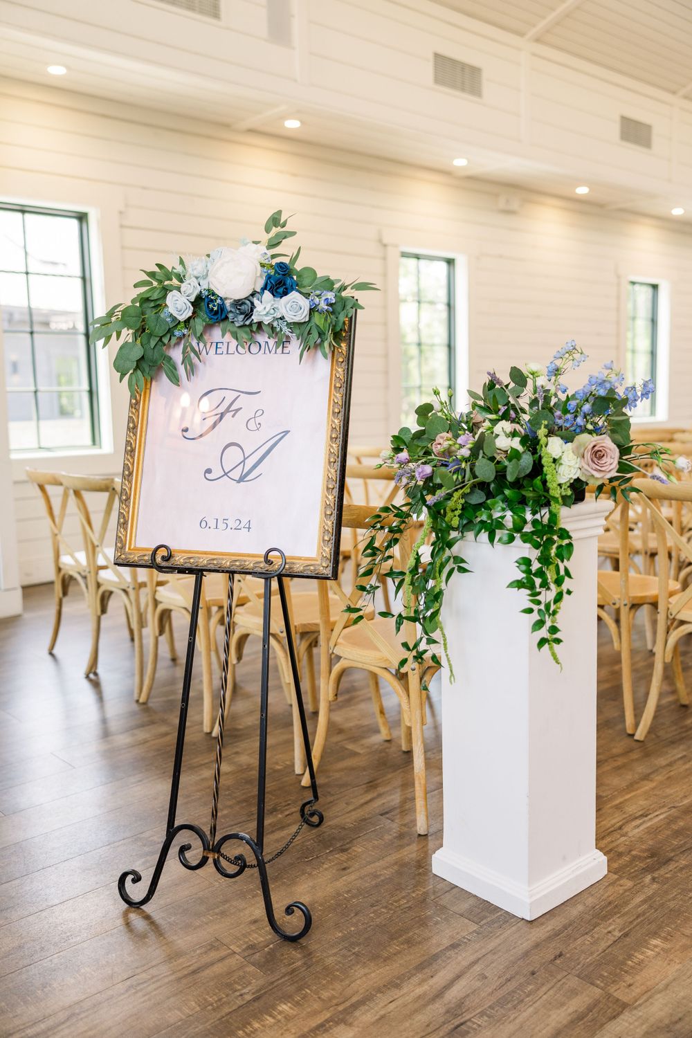 Elegant wedding decor featuring a gold-framed monogram sign and floral arrangements in a white room.