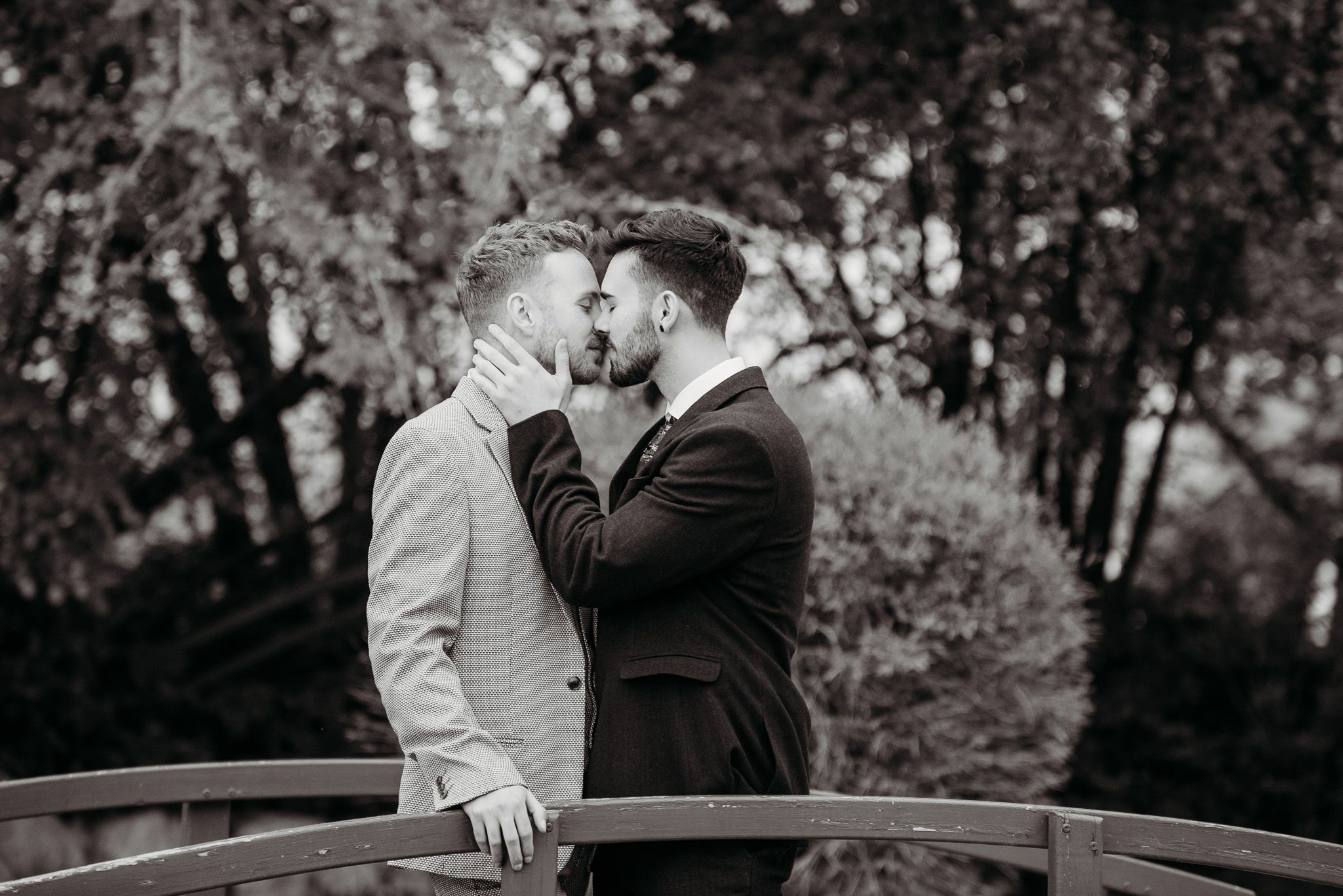 Intimate black and white portrait of couple sharing romantic moment on bridge.