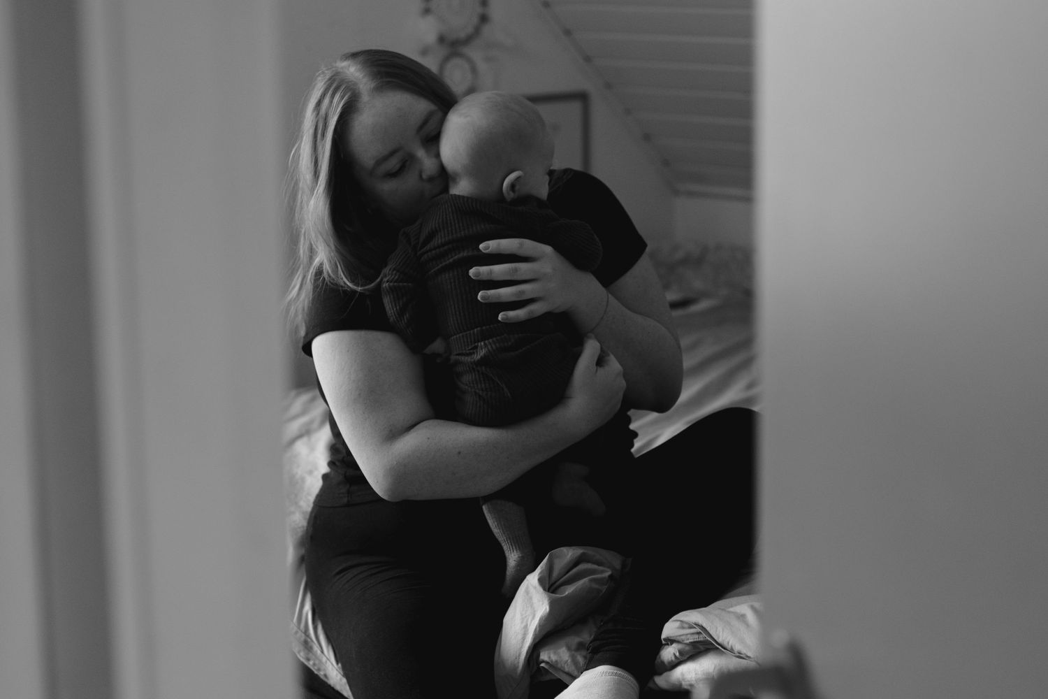 Intimate monochrome portrait of nurturing embrace in soft lighting.