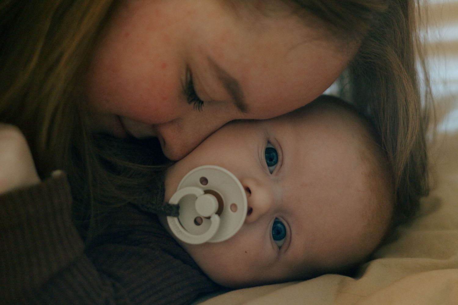 A tender moment showing a parent's love as they cuddle with a baby using a pacifier.