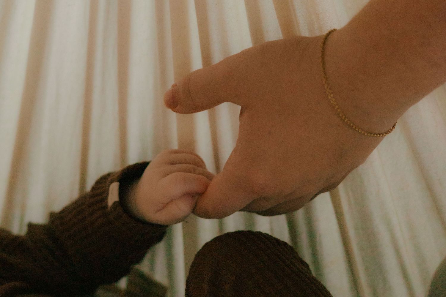Intimate close-up of small hands reaching for each other.
