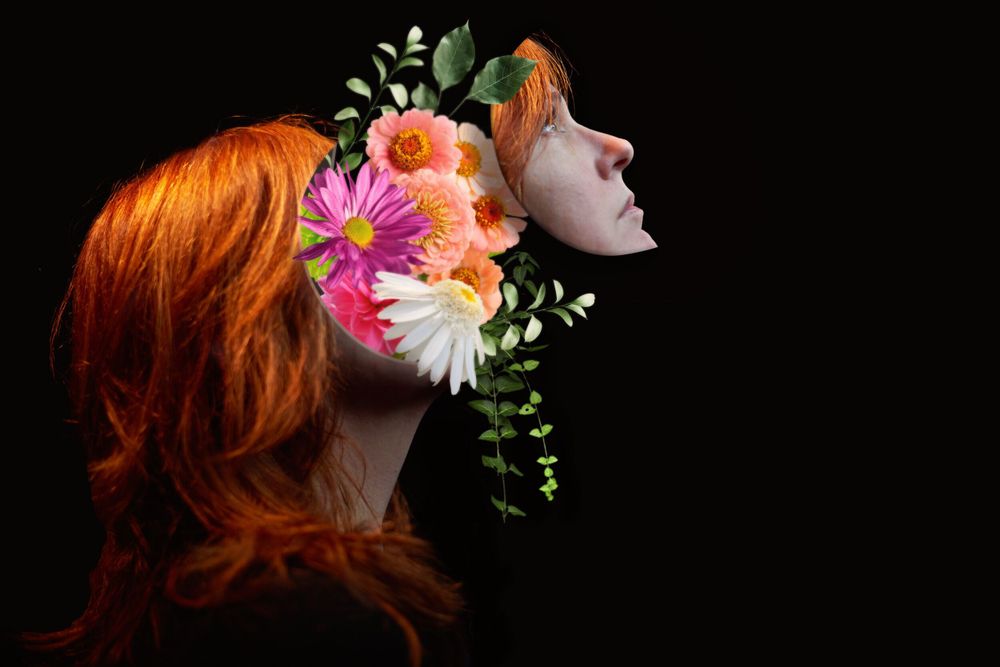 Artistic side profile portrait adorned with vibrant flowers against a dark backdrop.