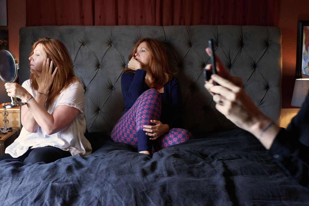 Three people lounging on a dark couch looking at their phones in different directions.