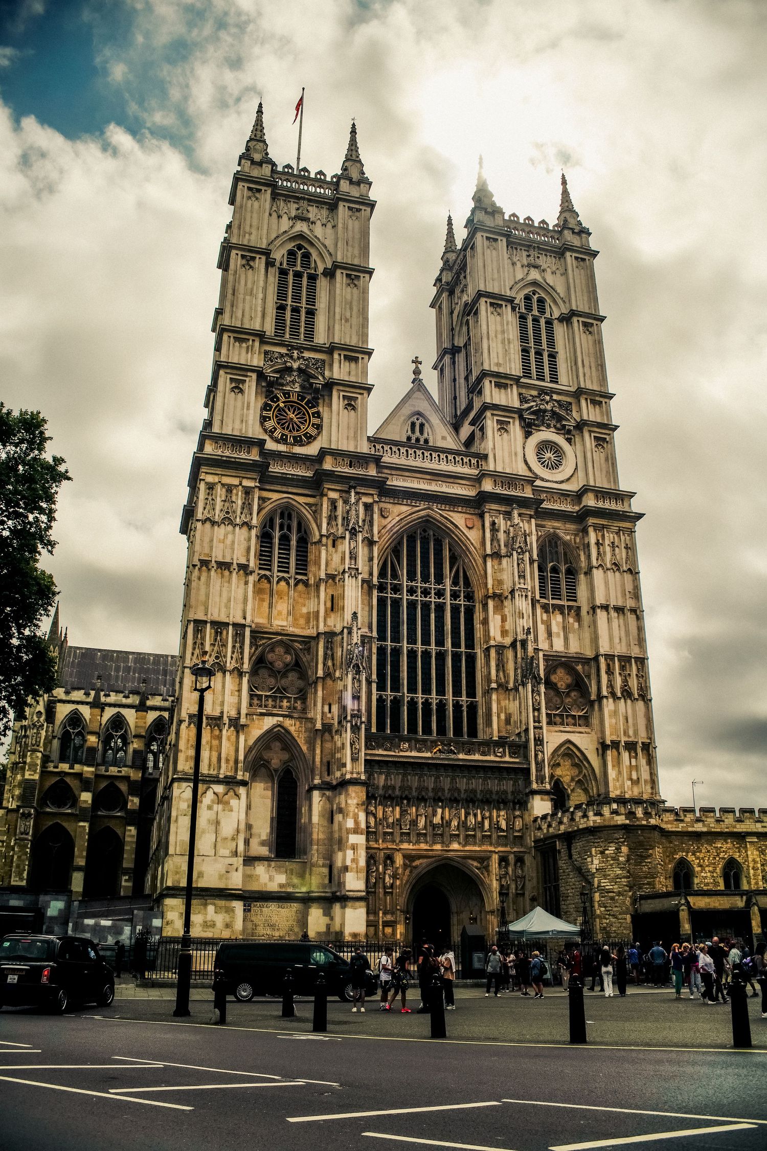 Westminster Abbey's Gothic facade towers against cloudy skies in central London.