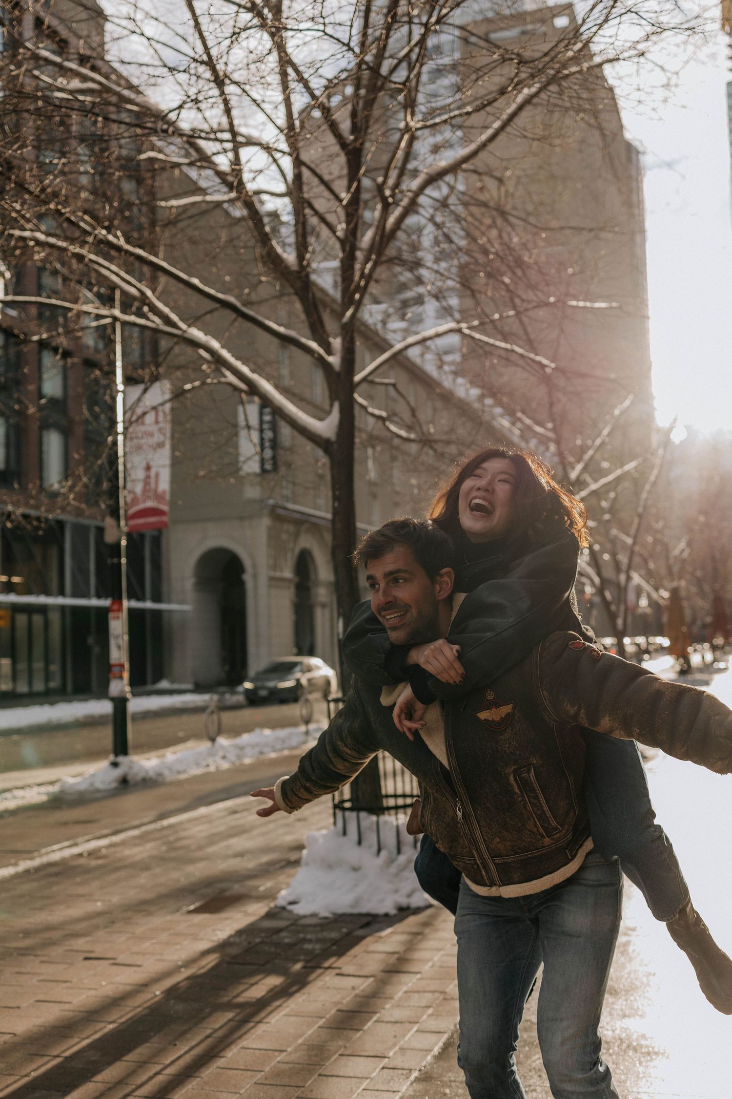 Male carrying his girlfriend on the back and running aroung in Toronto Downtown during sunset