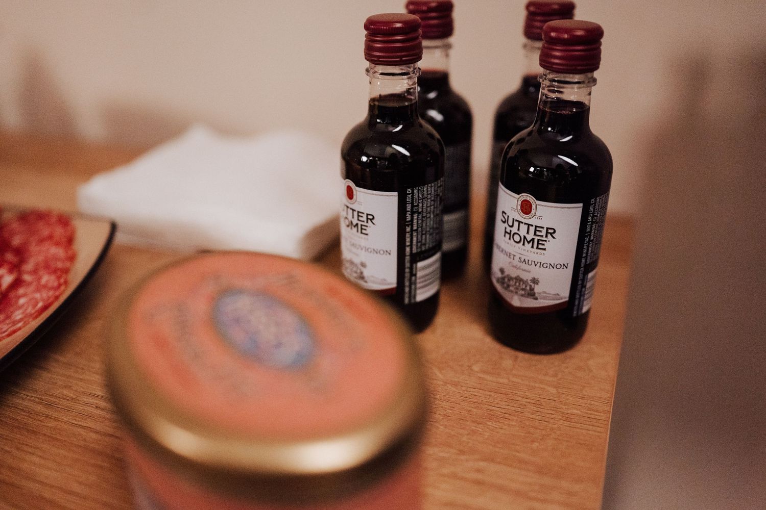 Several small dark liquor bottles and what appears to be a wooden coaster or plate on a wooden surface.