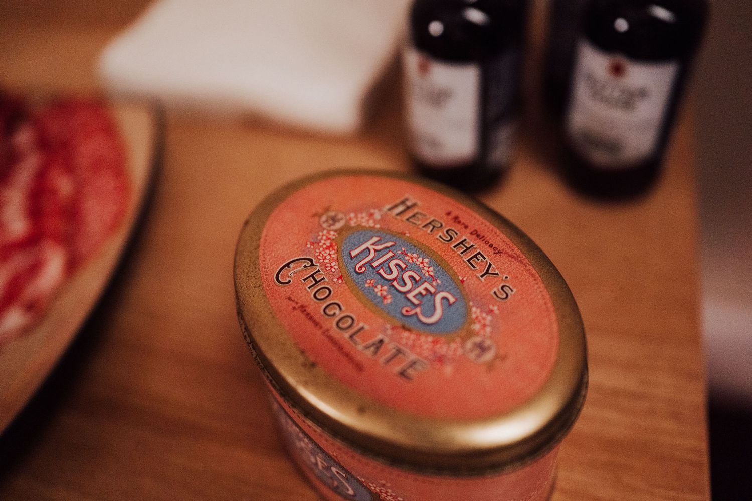 Close-up shot of a vintage metal tin with wine bottles visible in the background.