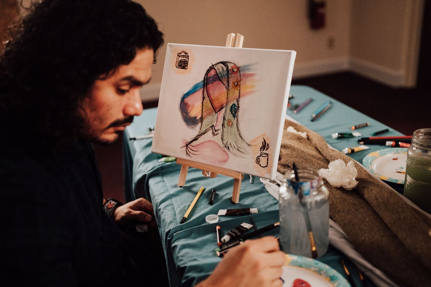 Fiancé paints a portrait of his fiancée at Sip and Paint date night event at Nicolle Aponte Photography studio in Middletown, PA