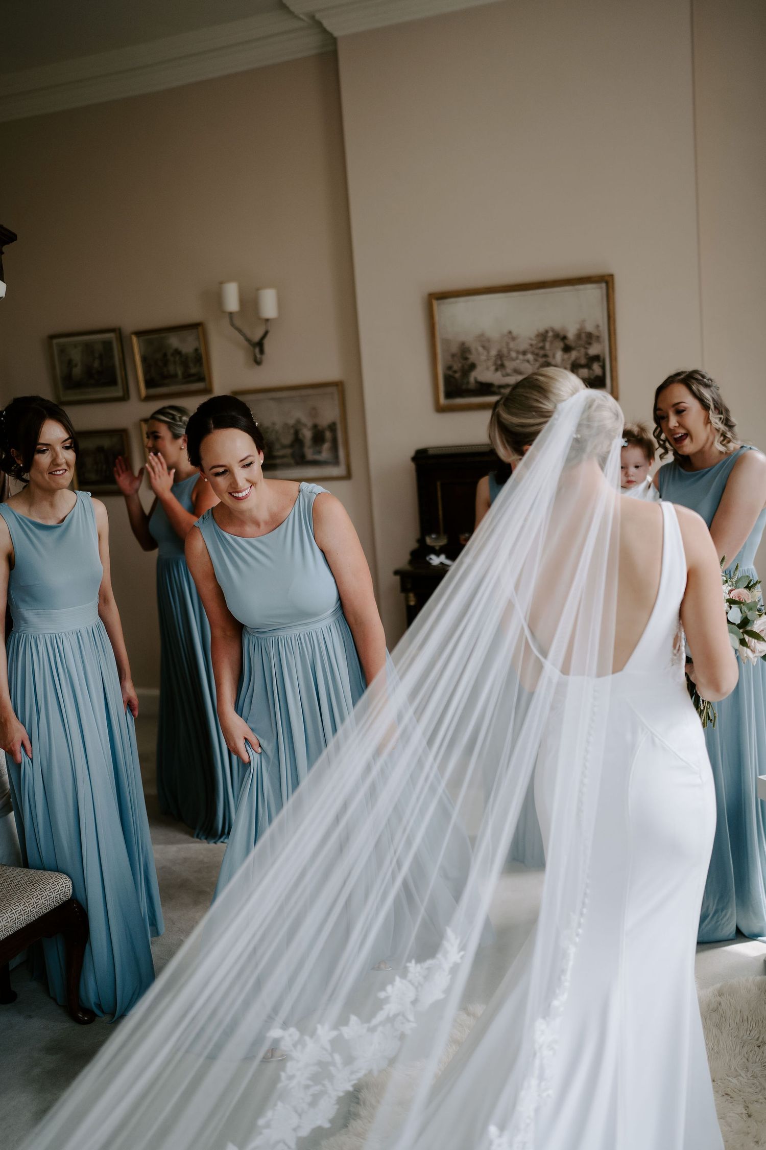 bridesmaids smiling and admiring bride and her dress at Iscoyd park