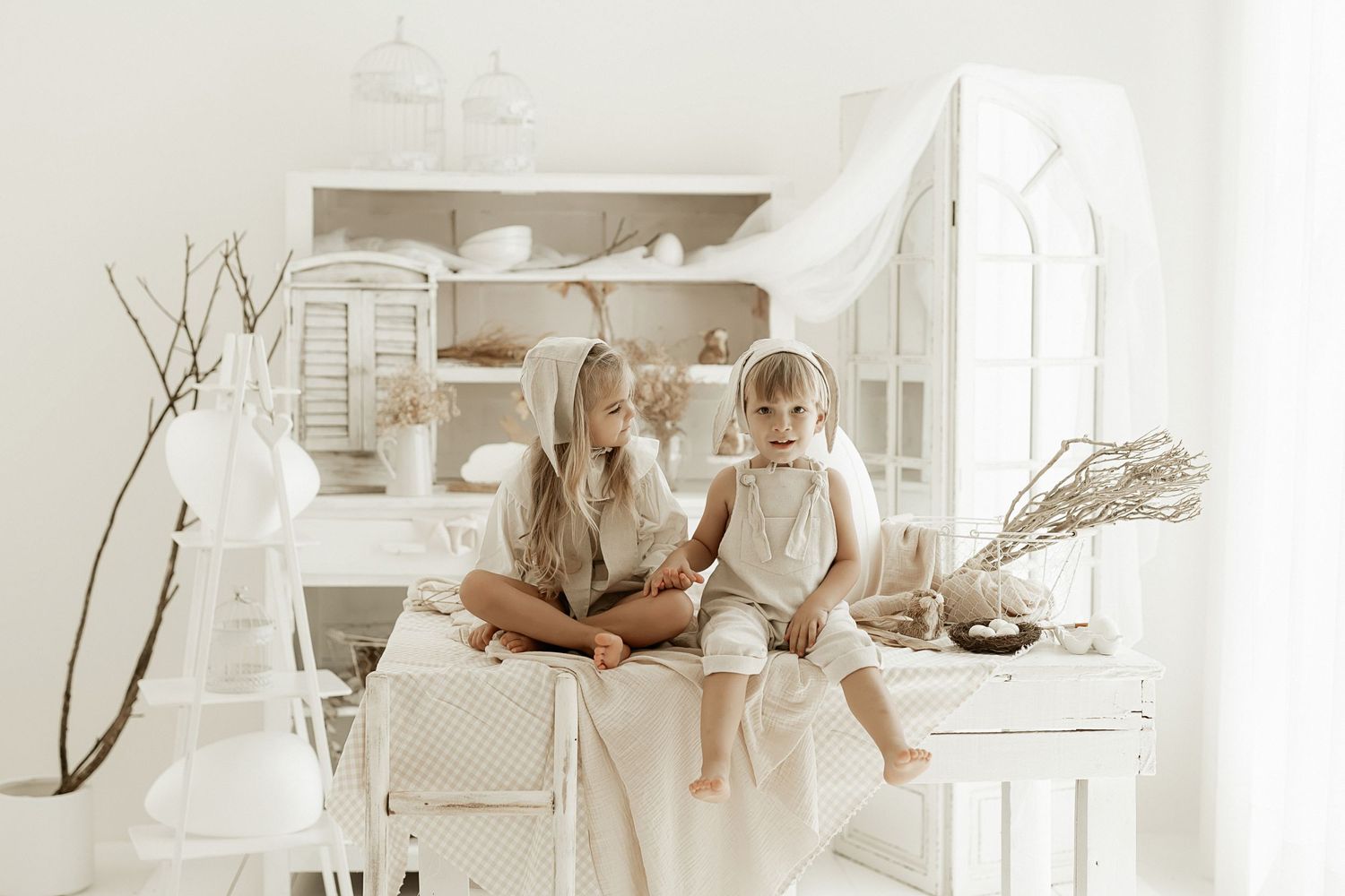 Two people sit together in a bright white kitchen with open shelving and rustic decor elements.