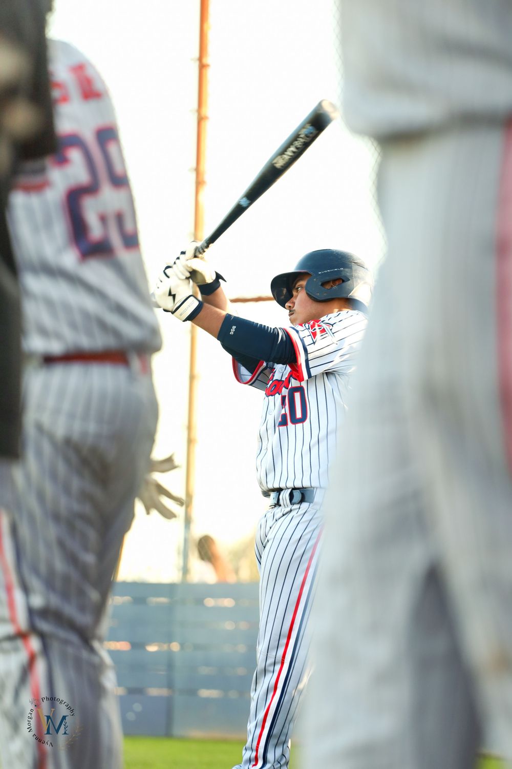 Baseball player in pinstriped uniform practicing batting stance and swing.