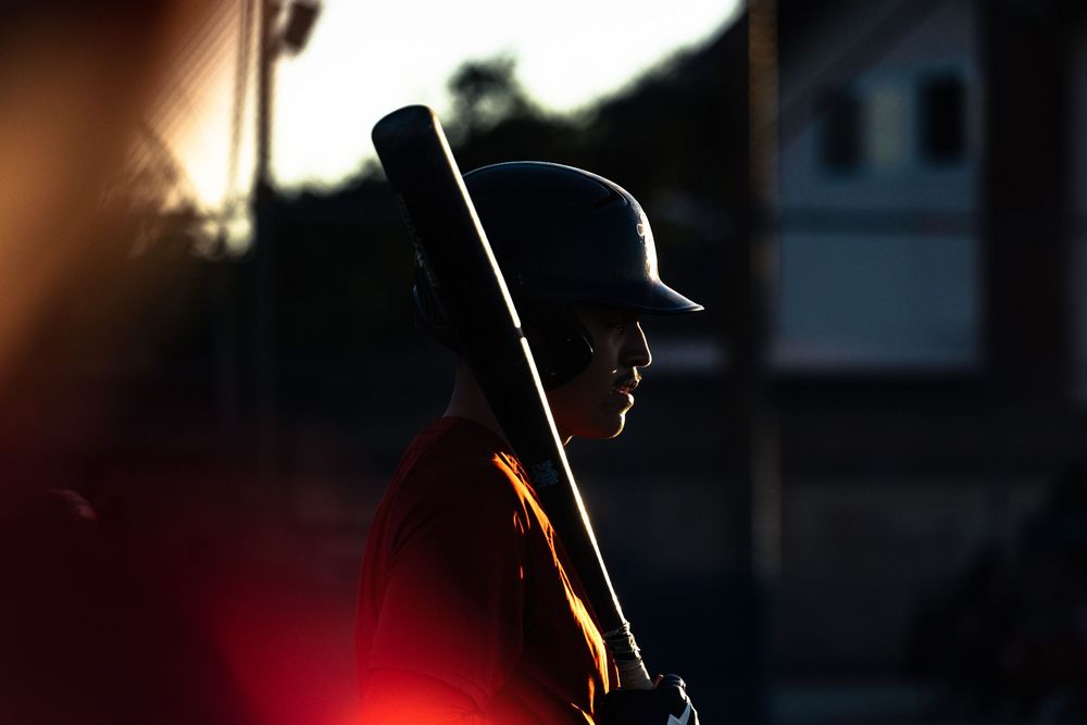 A silhouetted figure stands against a dramatic backlit background with warm glowing light creating a moody atmosphere.