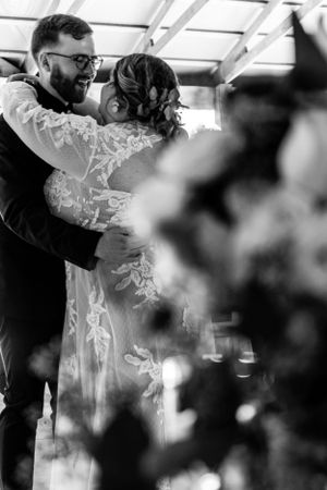 A bride and groom share their first dance at a wedding reception, captured in romantic black and white photography.