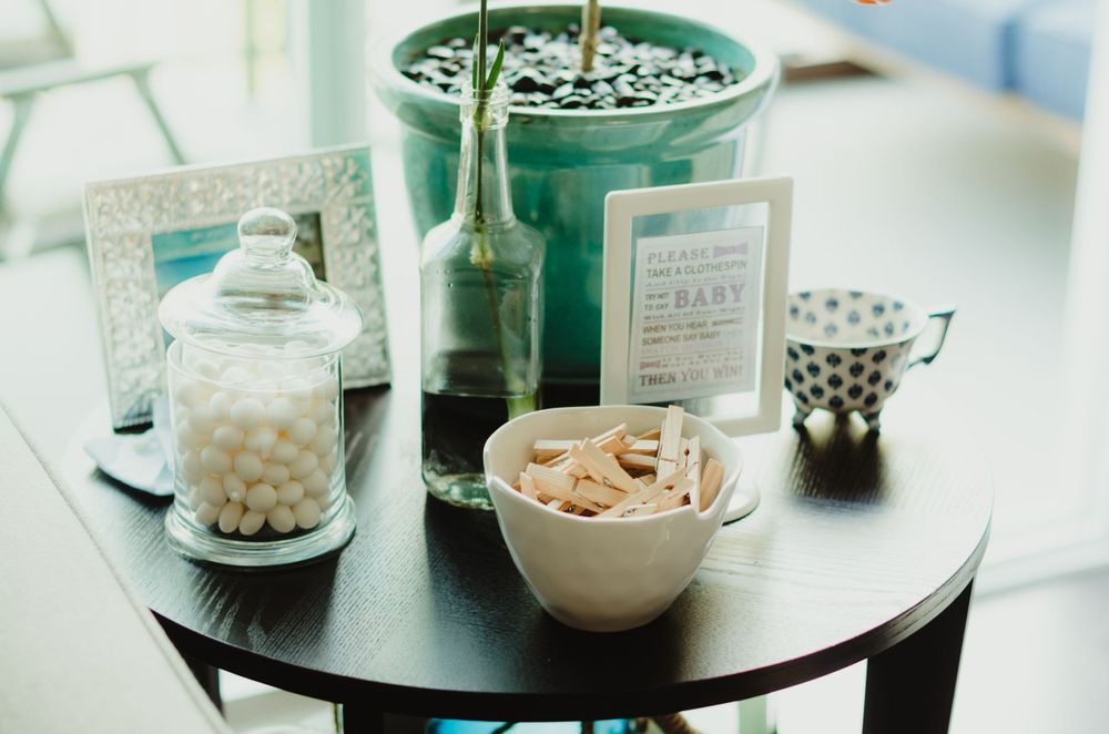 Glass jars with nuts and snacks alongside a potted plant on a round dark table.