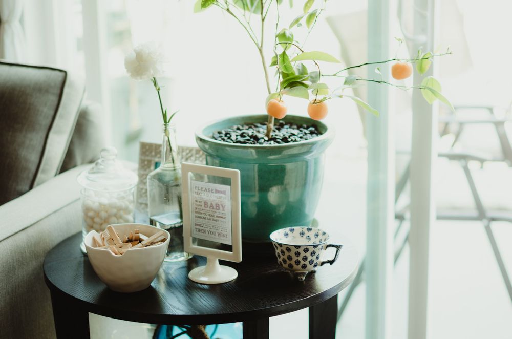 A cozy corner table with a turquoise planter, glass bottles, and decorative bowls in a sunlit room.