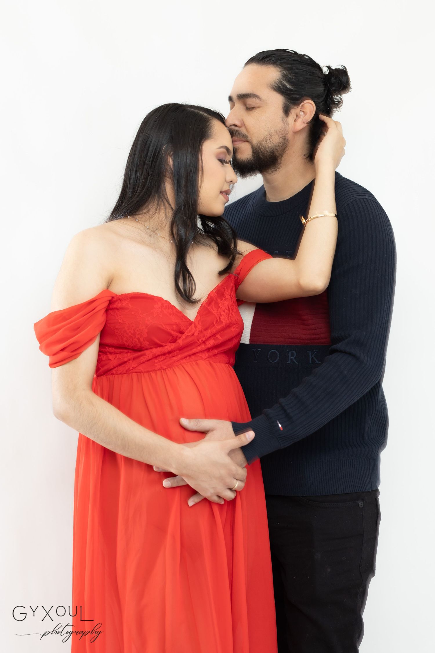 Intimate maternity portrait with couple in red dress and navy sweater.