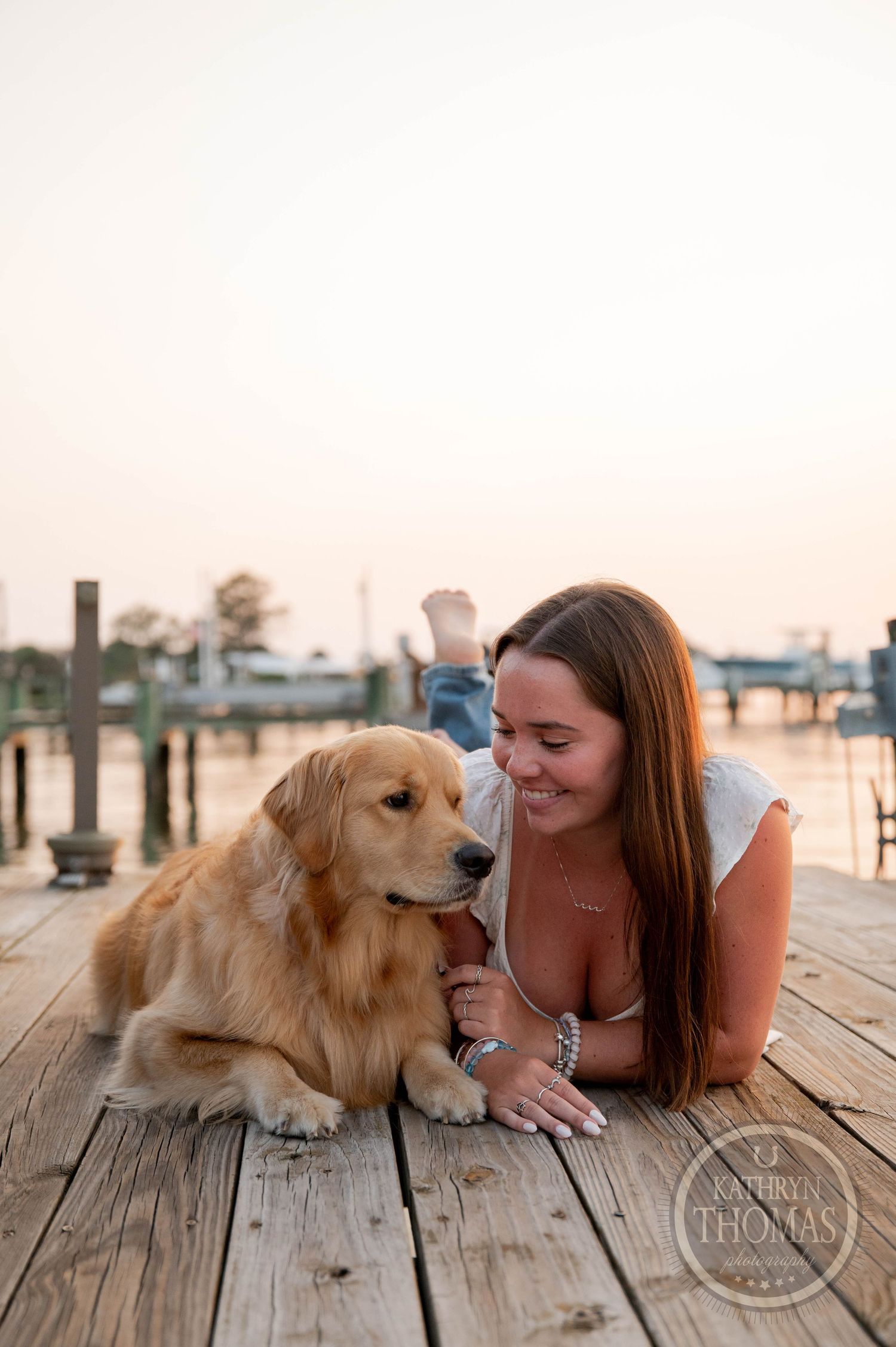 Golden Retriever and person sharing a close moment on waterfront dock.