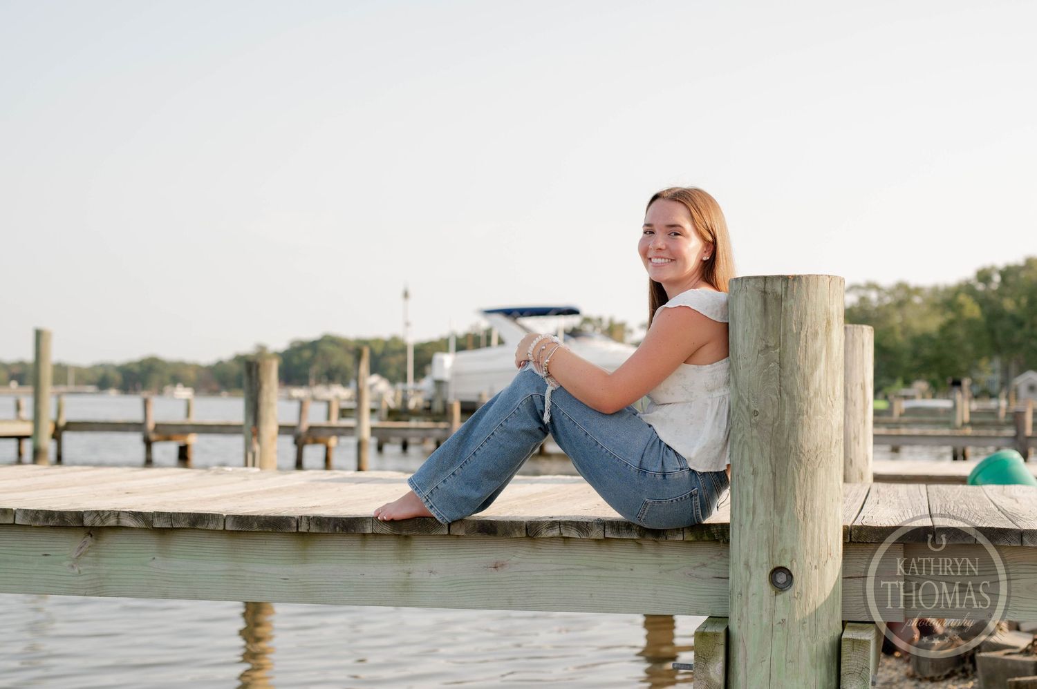 Person in casual attire relaxing on a wooden dock by the marina.