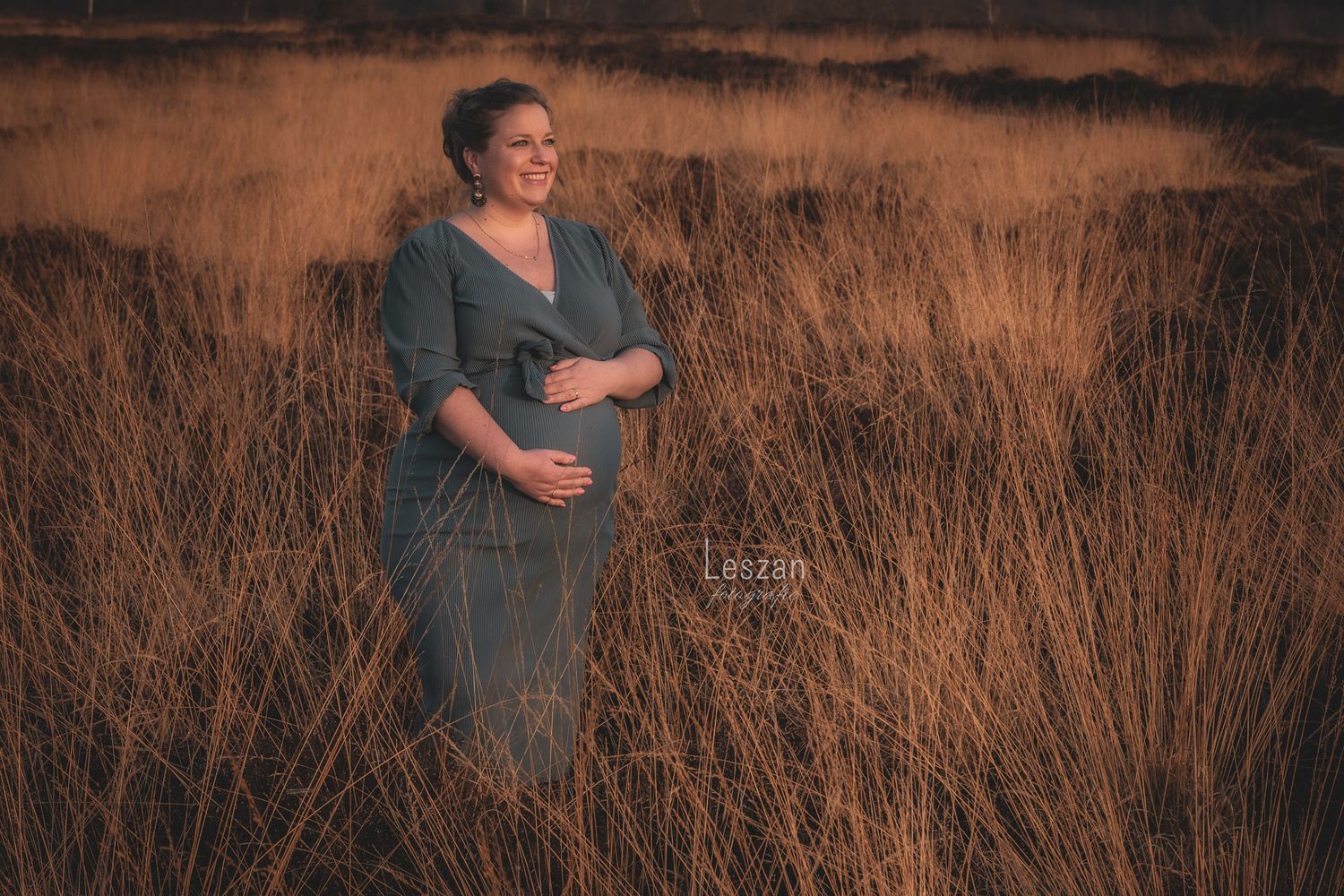 A figure stands in a field of tall brown grass during golden hour with a dreamy autumn atmosphere.