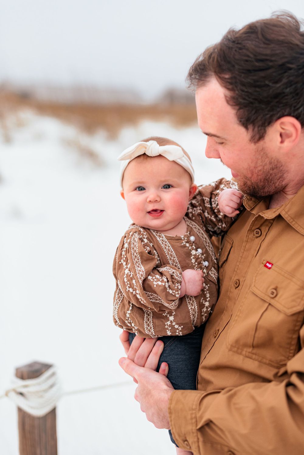 Snowy winter scene with baby in brown patterned clothing.