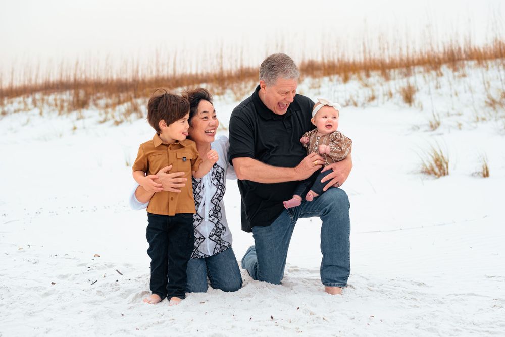 A tender family moment shared while kneeling together on white sand.