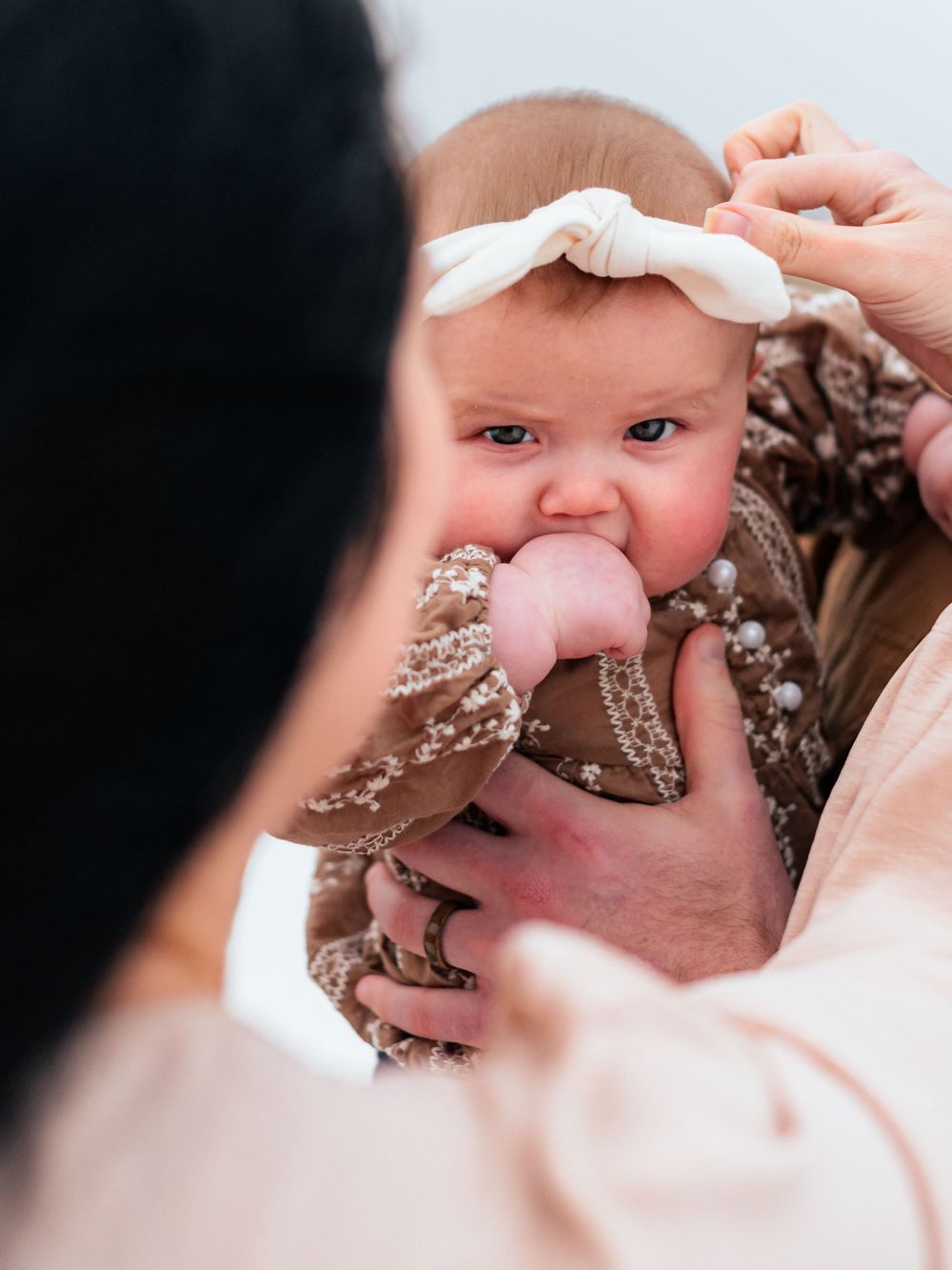 Close-up shot of baby wearing white headband against dark background.