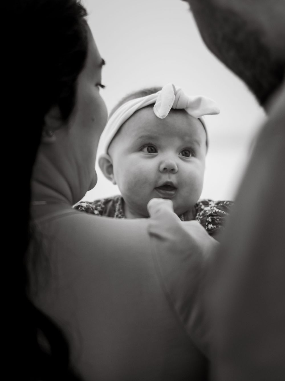 Black and white portrait of a baby with bow headband looking up with wonder.