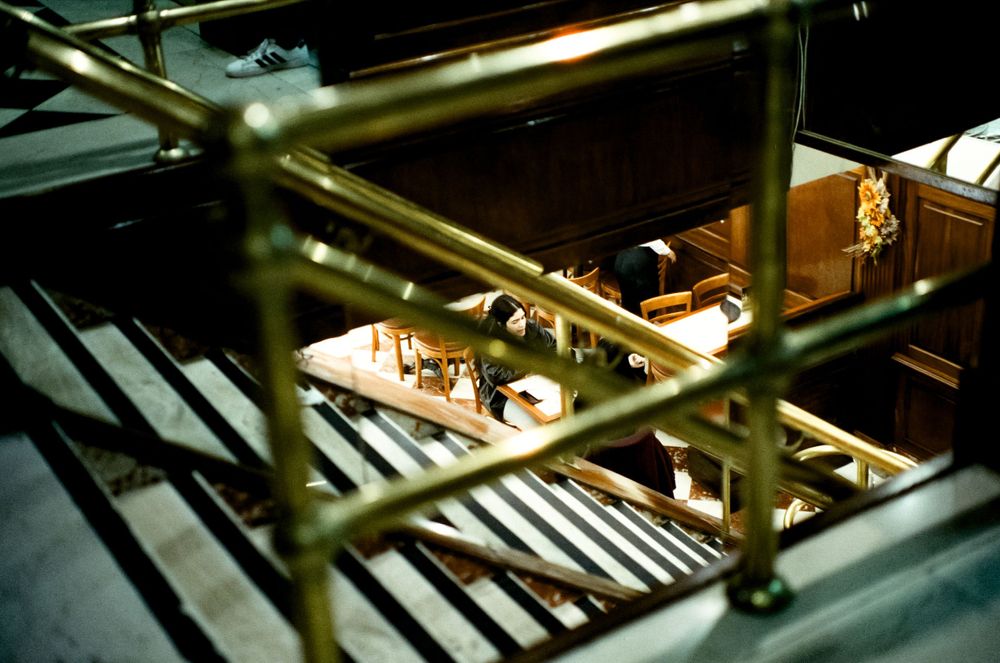 Industrial kitchen equipment viewed through metal railings in dim lighting.